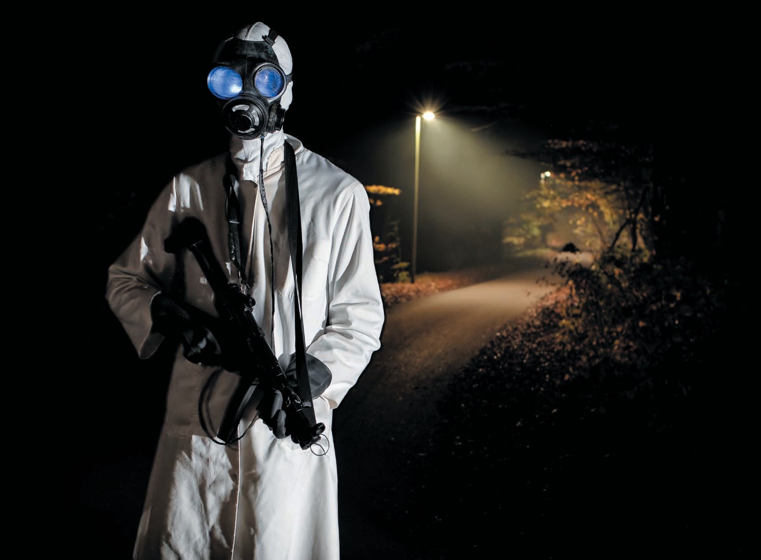 A person dressed in an intimidating outfit wearing a gas mask and holding a gun.
